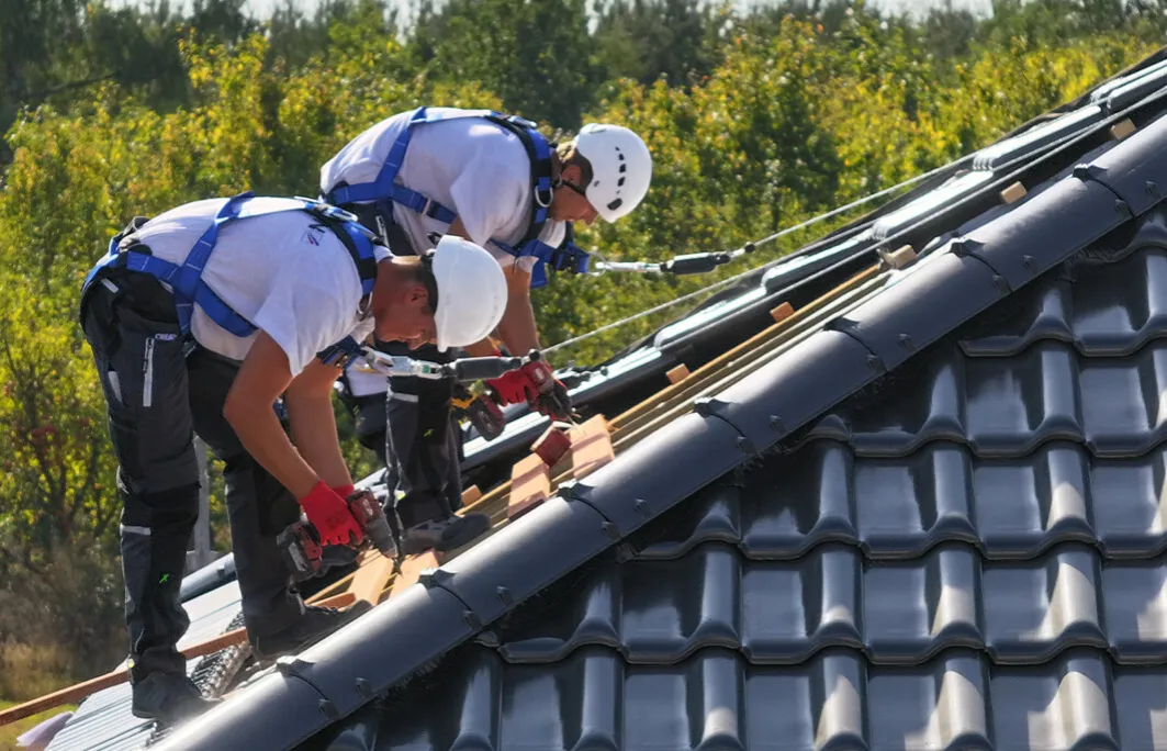 Dekarz podczas pracy na nowoczesnym dachu z dachówki ceramicznej