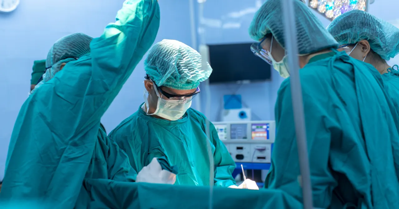 Zesp&oacute;ł chirurg&oacute;w w zielonych fartuchach podczas operacji. Może to być moment, gdy pacjent czeka na odszkodowanie za koronarografię.