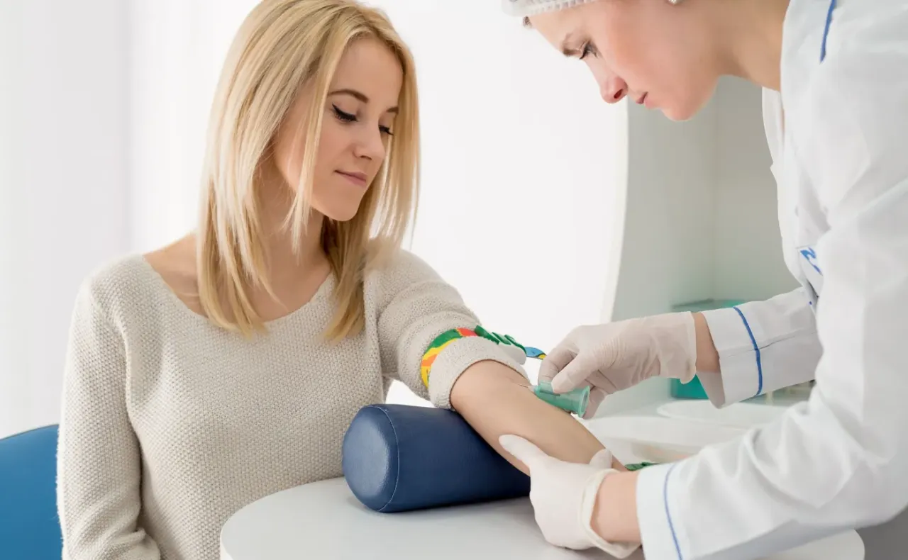 Kobieta z blond włosami czeka na pobranie krwi. Skierowanie na badania krwi jest ważne, aby sprawdzić stan zdrowia.