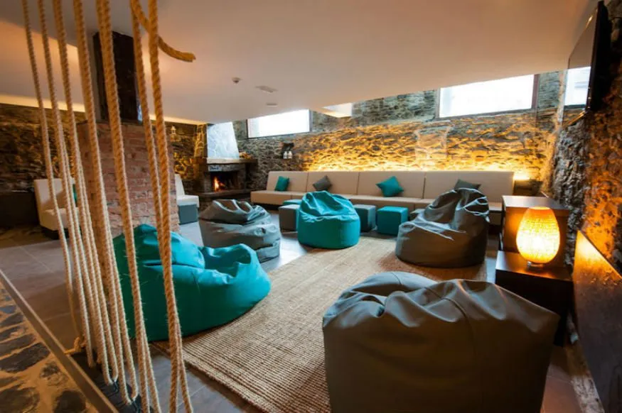 Wnętrze nowoczesnego hostelu z ludźmi w strefie wsp&oacute;lnej