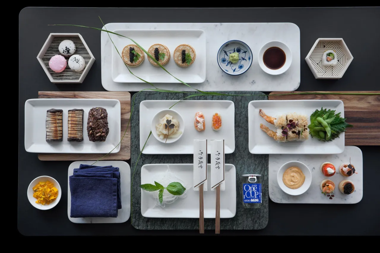 Elegancko podane przekąski, w tym mini naleśniki z kawiorem, sushi i makaroniki. Idealne inspiracje, jak zrobić sushi i inne smakołyki.