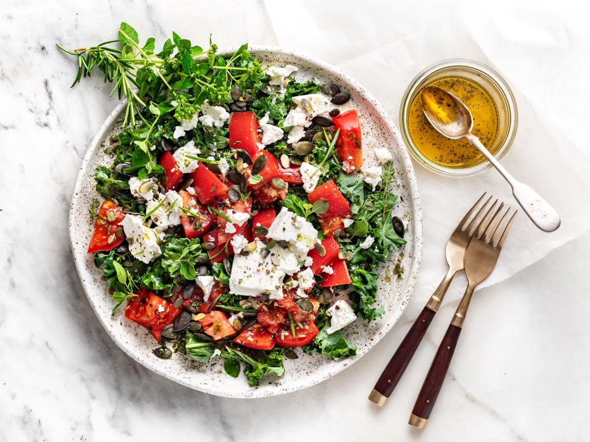 Kolorowa sałatka z jarmużem, pomidorami i fetą. Oto jak przygotować jarmuż do sałatki: posiekaj go drobno, by był delikatniejszy.