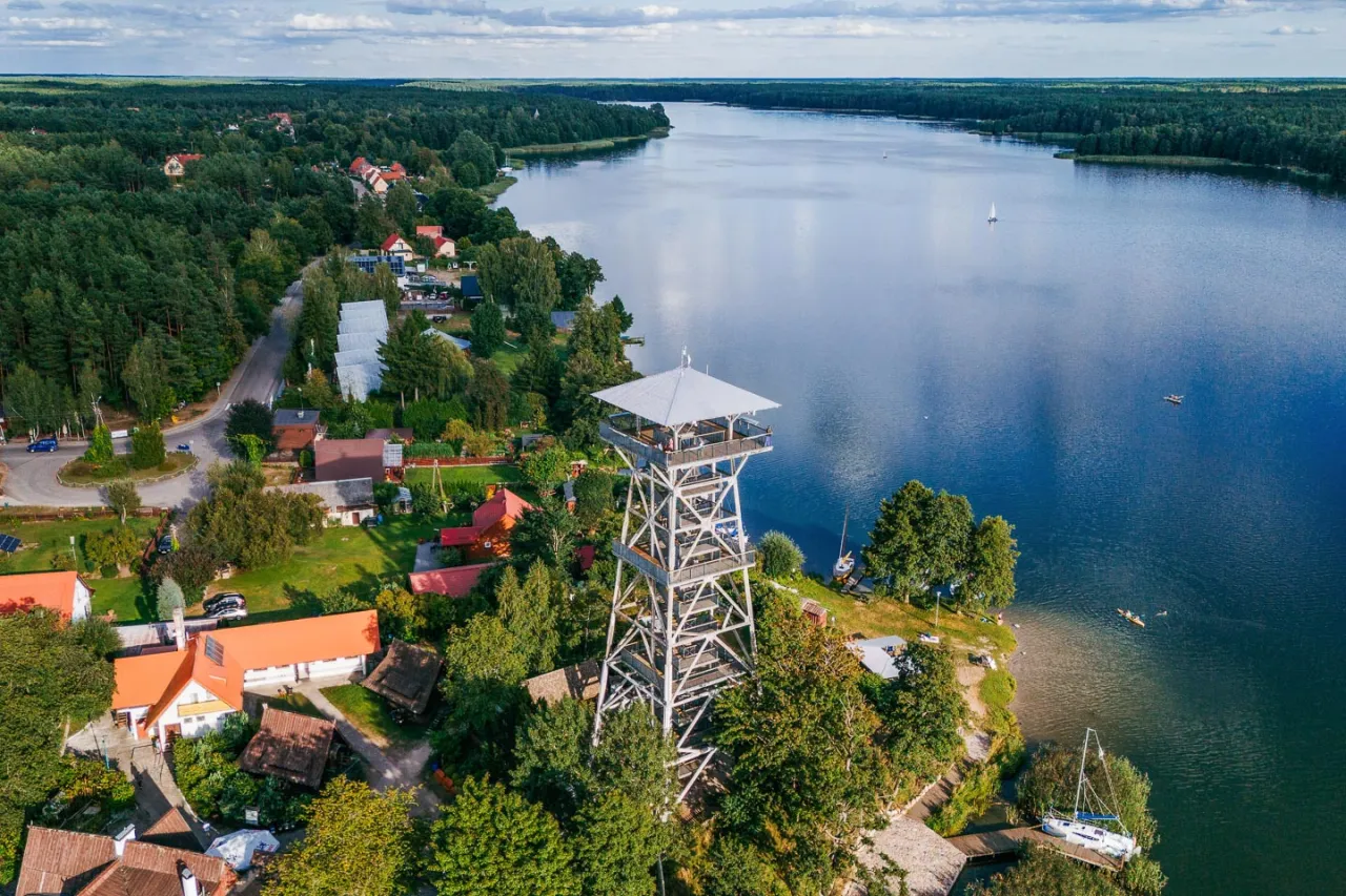 Wieża widokowa nad jeziorem, idealne miejsce, by zobaczyć, co warto zobaczyć na Kaszubach. Wokół lasy i urokliwe domki.