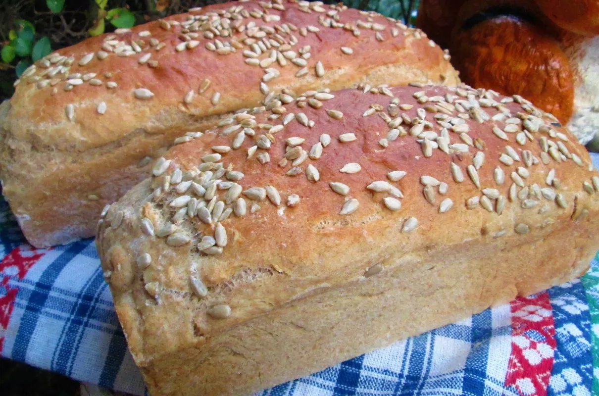 Dwa świeżo upieczone bochenki chleba posypane słonecznikiem. Idealny przykład, jak upiec chleb w domu.