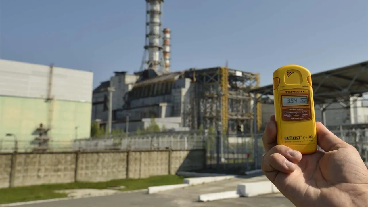 Żółty dozymetr pokazuje 3.94 µSv/h przed budynkiem elektrowni. Czy reaktor w Czarnobylu jest aktywny? Nie, ale promieniowanie wciąż jest obecne.