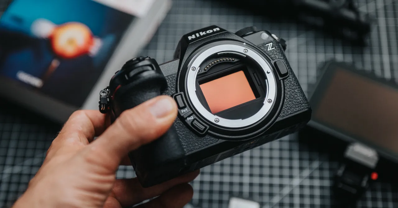 Dłoń trzyma aparat lustrzanka Nikon Z z widoczną matrycą.