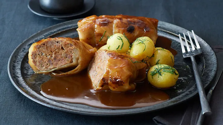 Herzhafte deutsche Kohlrouladen mit So&szlig;e auf einem Teller