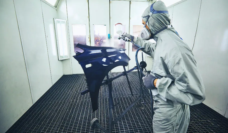 Samochód w komorze lakierniczej, lakiernik przy pracy