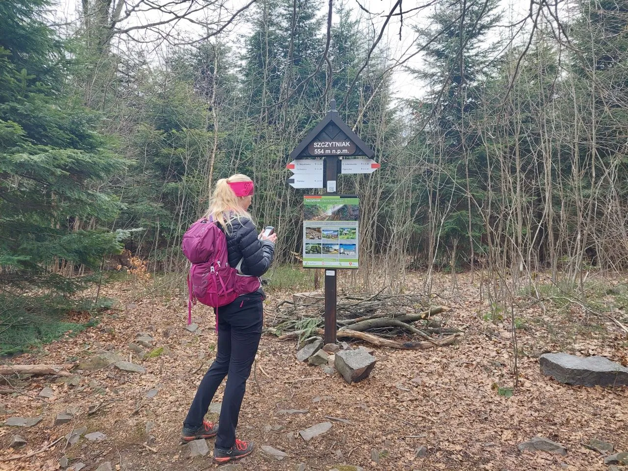 Turystka z plecakiem przy znaku szczytu Szczytniak (554 m n.p.m.) w rezerwacie przyrody.