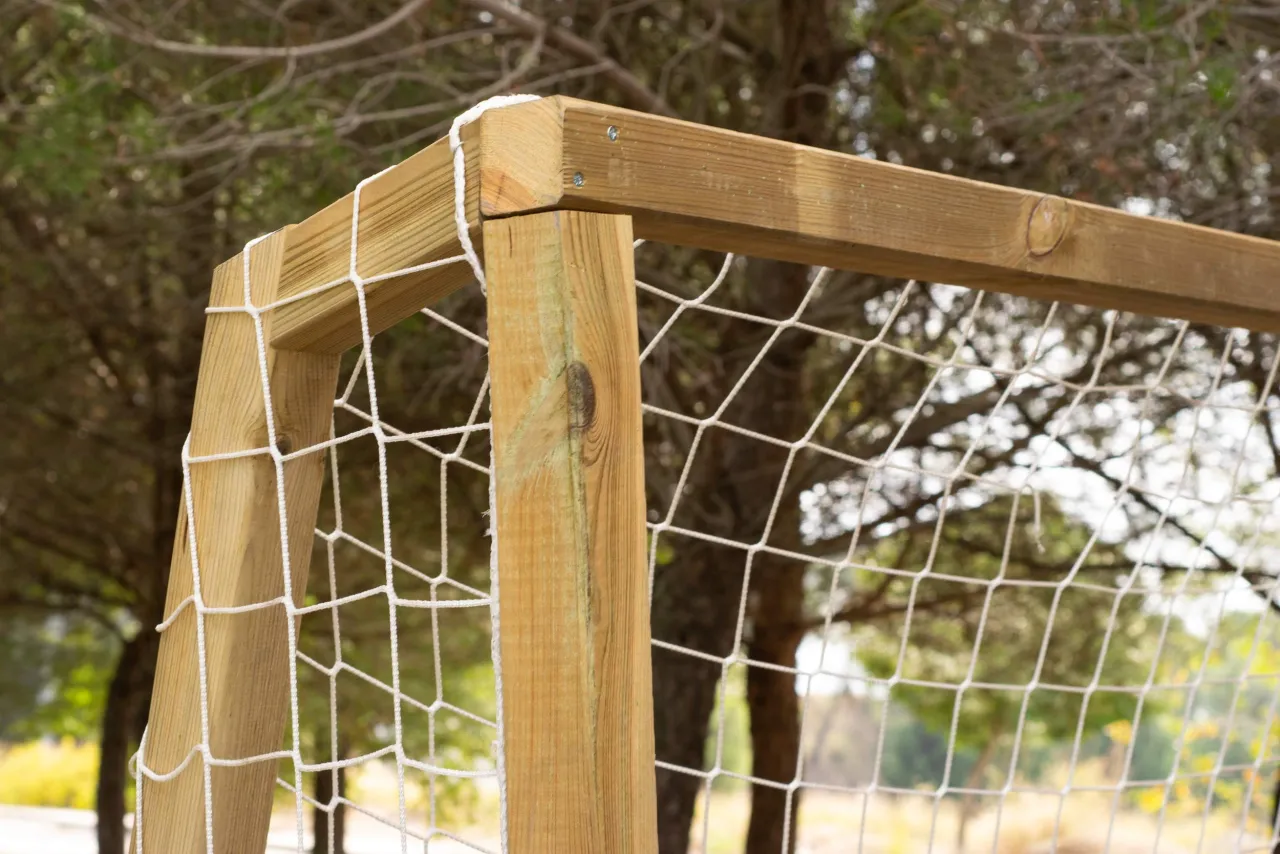 Drewniana konstrukcja bramki do piłki nożnej, z siatką. Idealna do zabawy na świeżym powietrzu, pokazuje z czego zrobić bramkę do piłki nożnej.