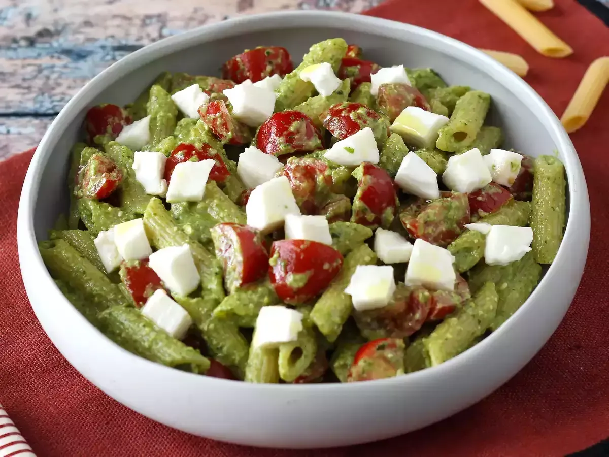 Makaron penne z zielonym pesto, pomidorkami koktajlowymi i kostkami mozzarelli. Idealny pomysł, co zrobić z rukoli na obiad.