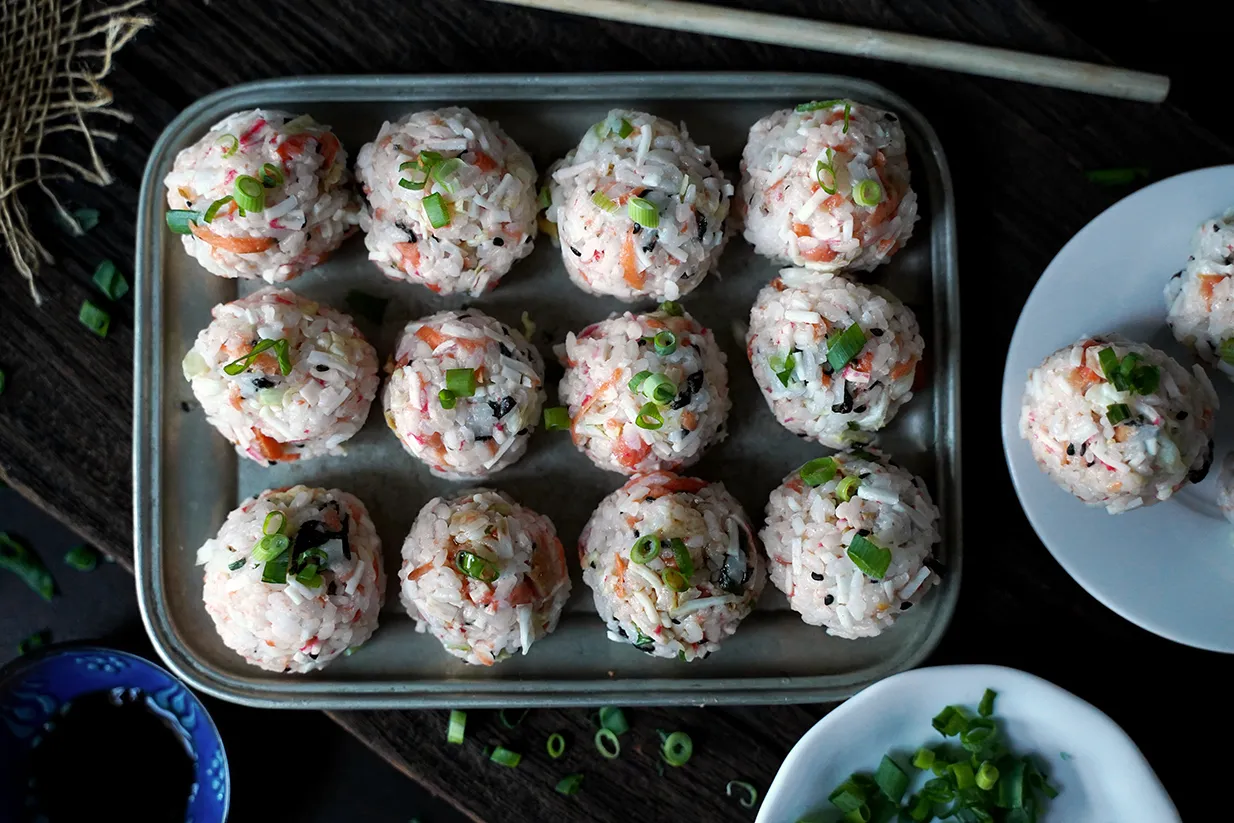 Urocze kulki sushi z ryżu, łososia i szczypiorku, ułożone na metalowej tacy, gotowe do podania.