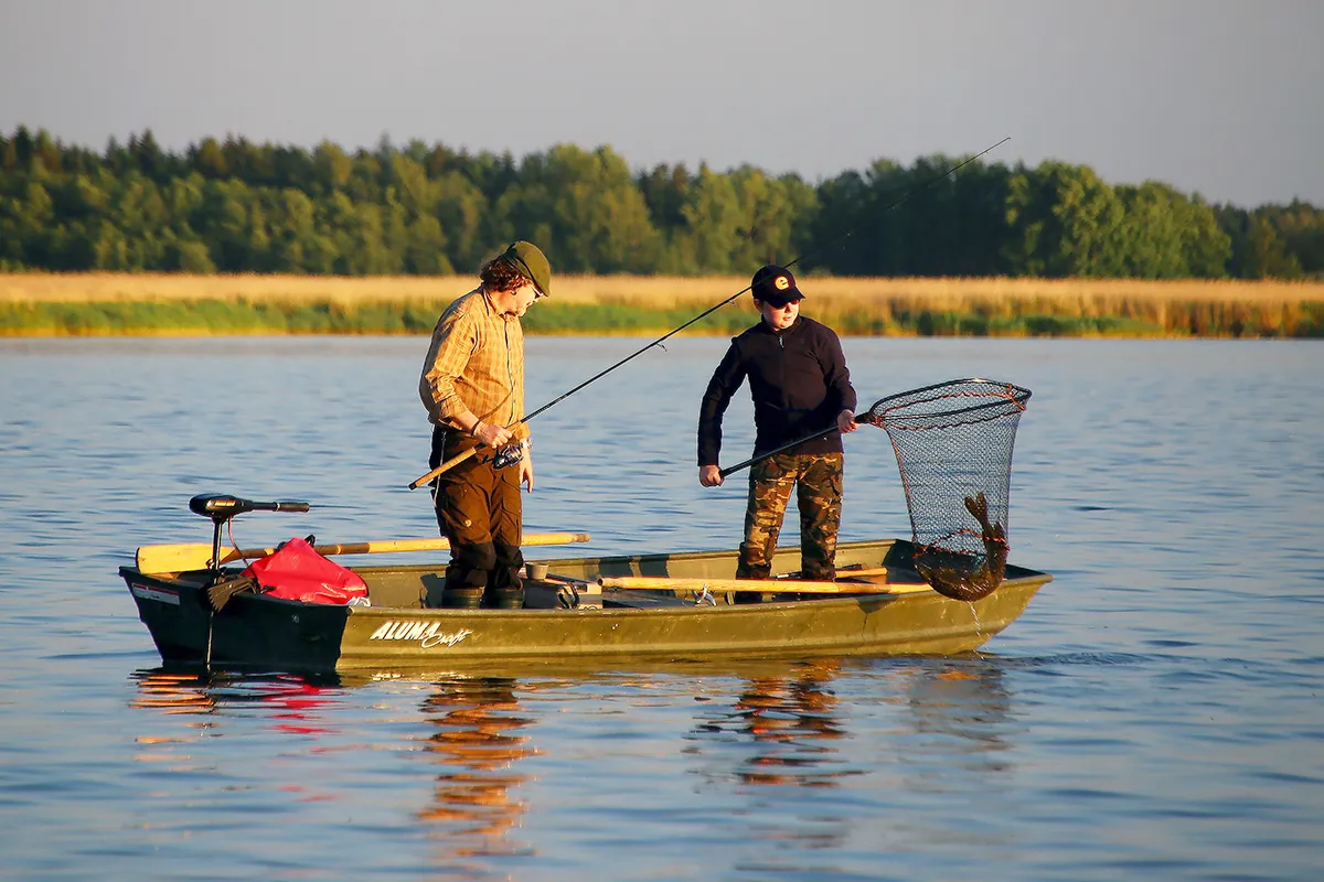 Wędkarz łowiący ryby z pomostu przy domku nad jeziorem