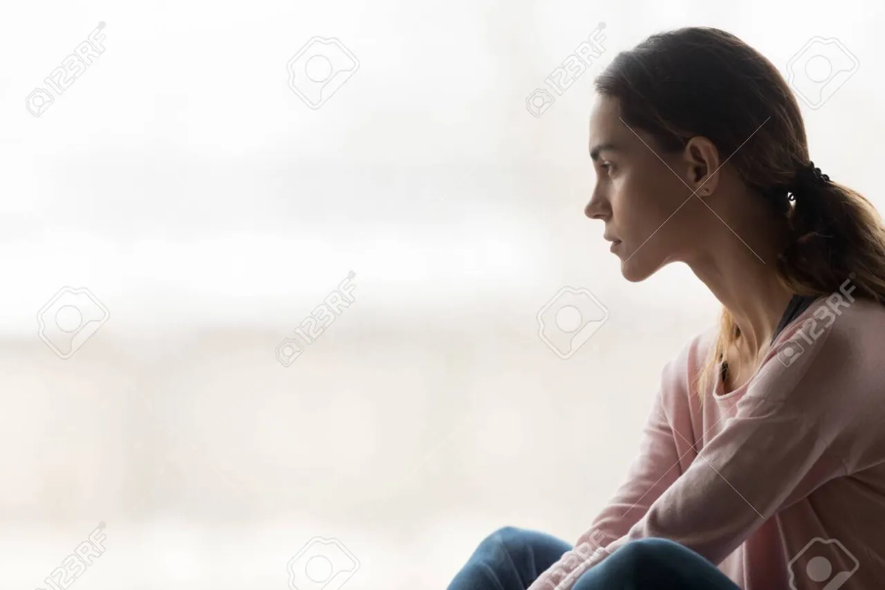 smutna, zamyślona osoba siedząca samotnie w pokoju