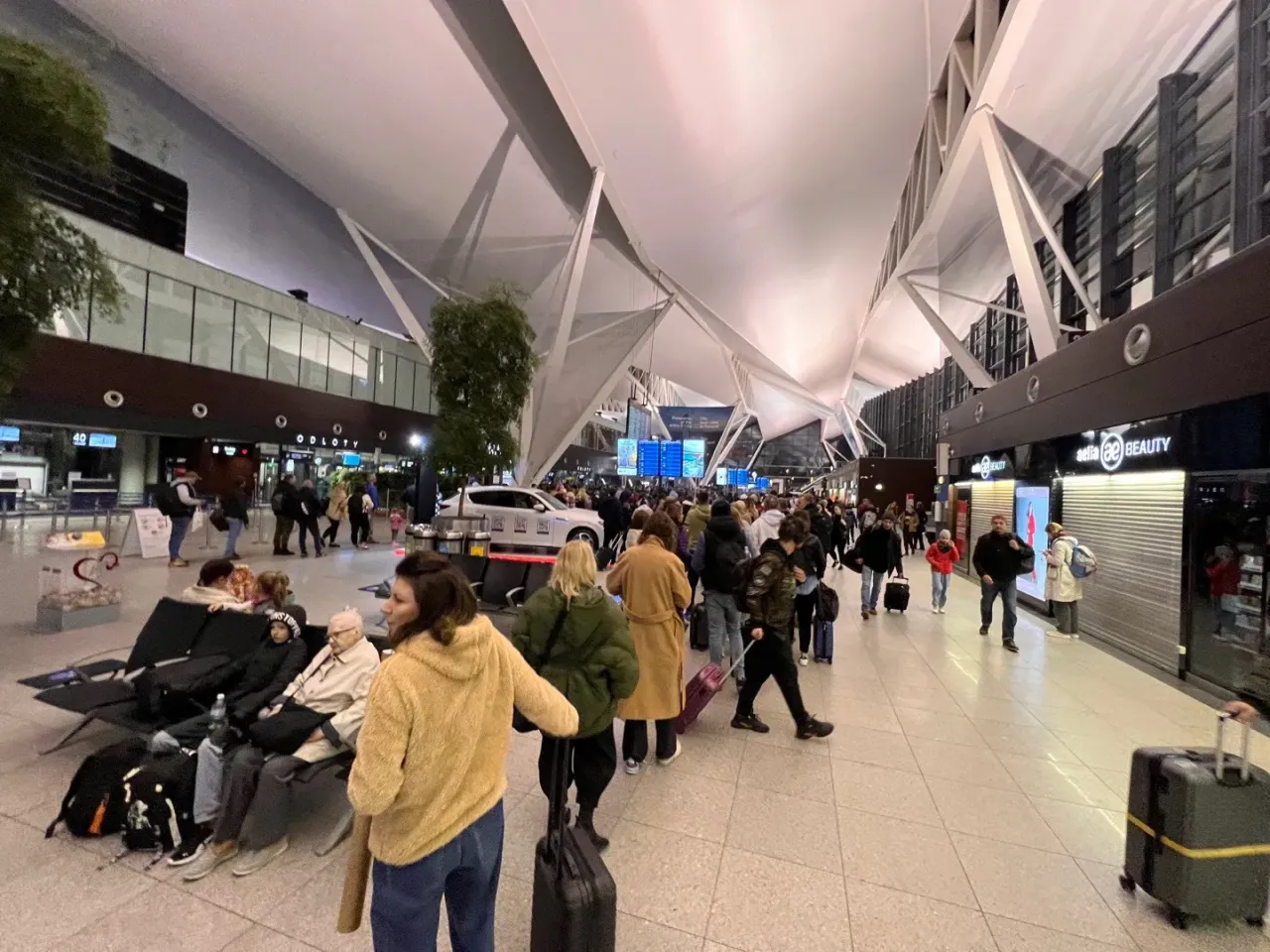 Tłum ludzi w terminalu odlot&oacute;w na lotnisku w Gdańsku. Wszyscy czekają na swoje loty, zastanawiając się, ile czasu zostało do odlotu.