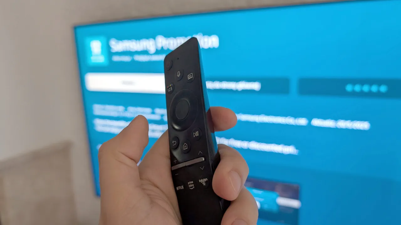 Pilot w dłoni, ekran telewizora z niebieskim tłem. Dowiedz się, jak zainstalować aplikacje na telewizorze.