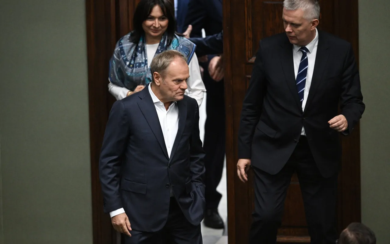 Donald Tusk, który rządził w latach 2007-2015, wchodzi do sali z innymi politykami.