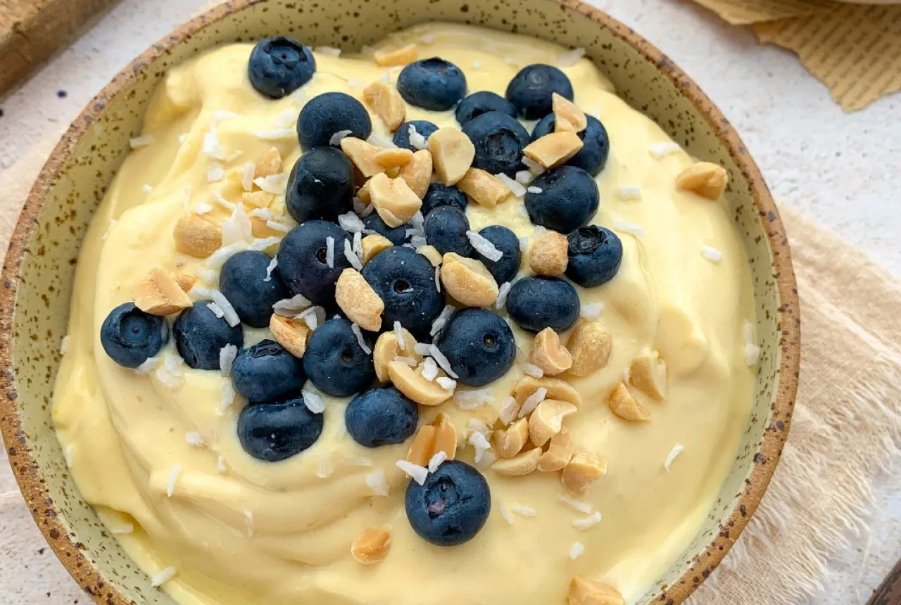 Pyszny deser z mrożonego mango, udekorowany borówkami, orzeszkami i wiórkami kokosowymi. Idealny pomysł, co zrobić z mrożonego mango!