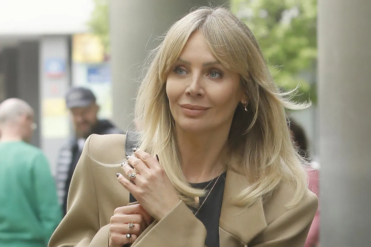 Agnieszka Woźniak-Starak w beżowym płaszczu, z biżuterią na dłoniach. Jej majątek budzi zainteresowanie.