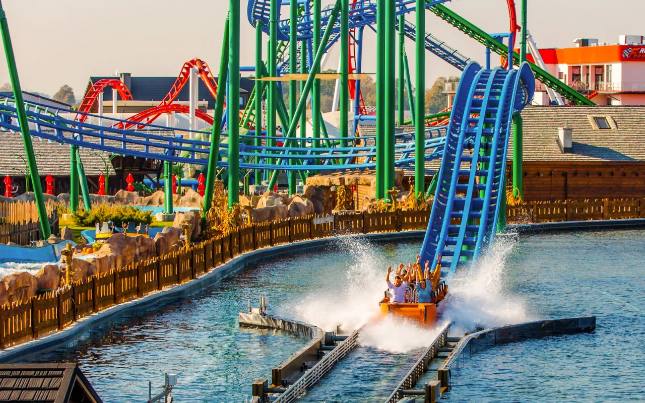 Zator Energylandia trasa wodnej kolejki g&oacute;rskiej z rozpryskującą się wodą i pasażerami machającymi rękami.