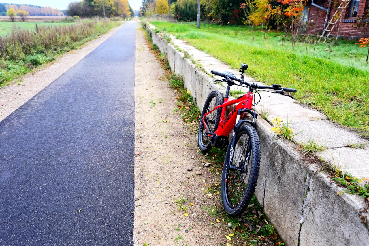 Czerwony rower g&oacute;rski czeka na przygodę na malowniczej trasie w Szczytnie. Jesienne liście dodają uroku.