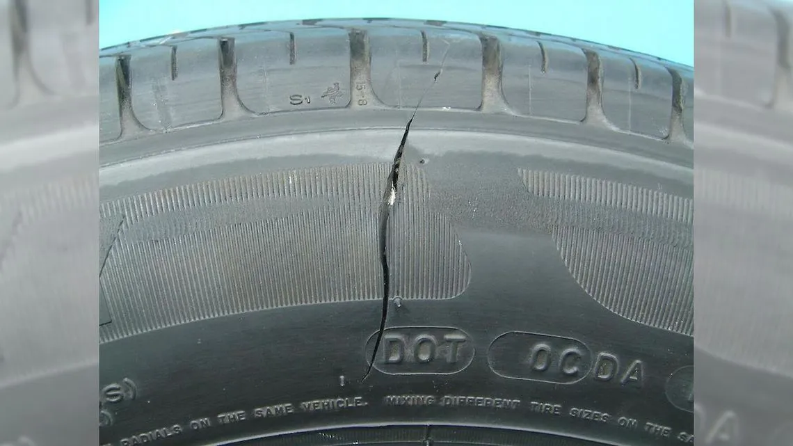 Oględziny opony samochodowej, osoba sprawdzająca bieżnik i ściany boczne pod kątem pęknięć