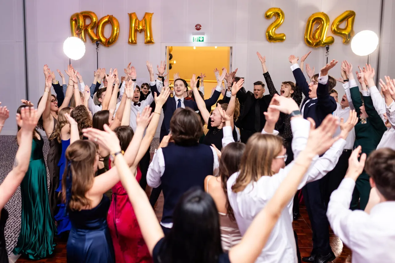 Fotograf na studniówce robiący zdjęcia grupie uczniów