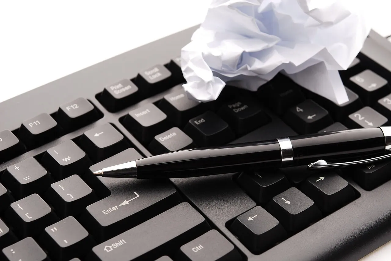 Klawiatura, długopis i zmięta kartka papieru. Jak uzyskać odpis z księgi wieczystej? To pytanie może być odpowiedzią na biurokratyczne wyzwania.