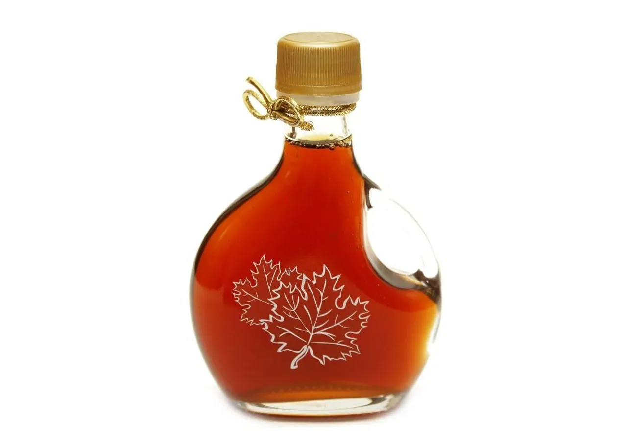 Mała butelka syropu klonowego z liściem klonu. Czy syrop klonowy jest zdrowy? Warto sprawdzić!