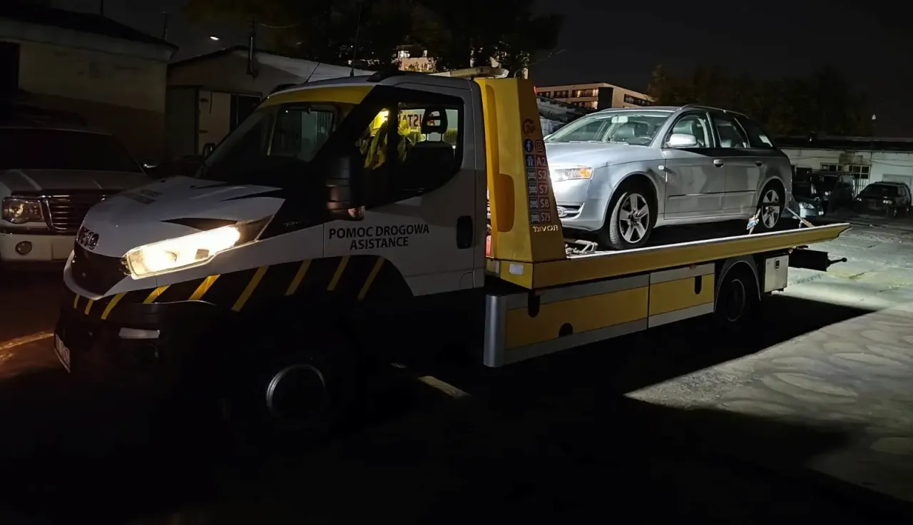 Pomoc drogowa assistance to ratunek w potrzebie. Auto na lawecie, nocą, czeka na dalsze działania.