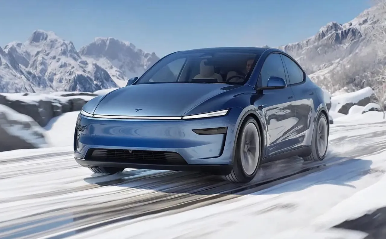 Niebieska Tesla Model Y pokonuje śnieżną drogę wśr&oacute;d g&oacute;r. Idealna na zimowe wyprawy, kiedy nowa Tesla Y udowadnia swoją wszechstronność.