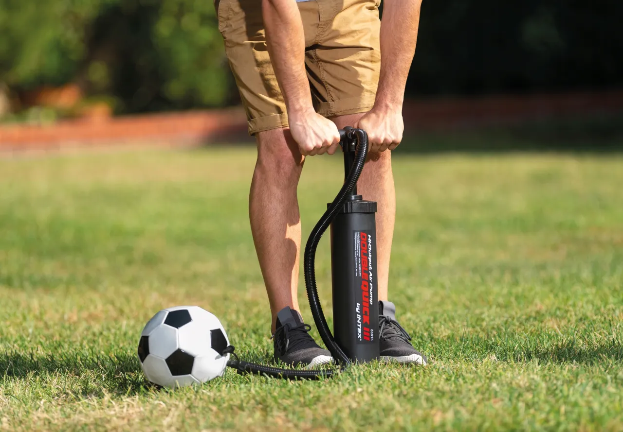 osoba pompująca piłkę gimnastyczną pompką ręczną