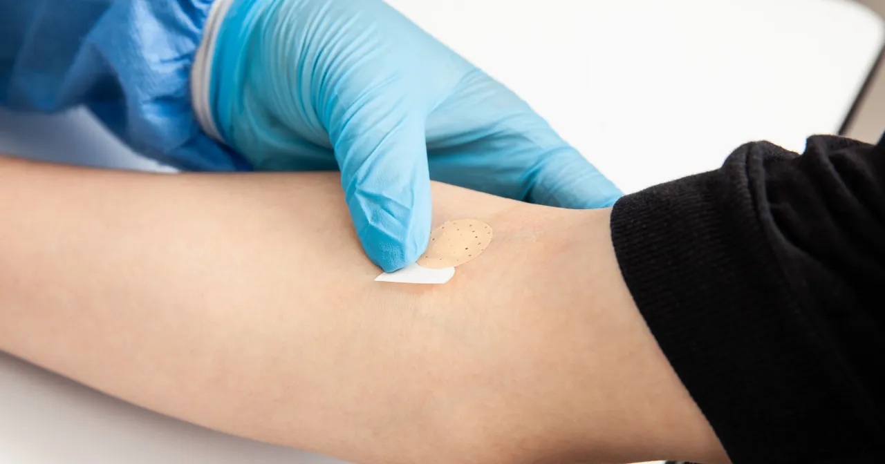 Rękawiczka medyczna zakłada plaster na ramię po pobraniu krwi. Badanie kortyzolu co to za badanie?