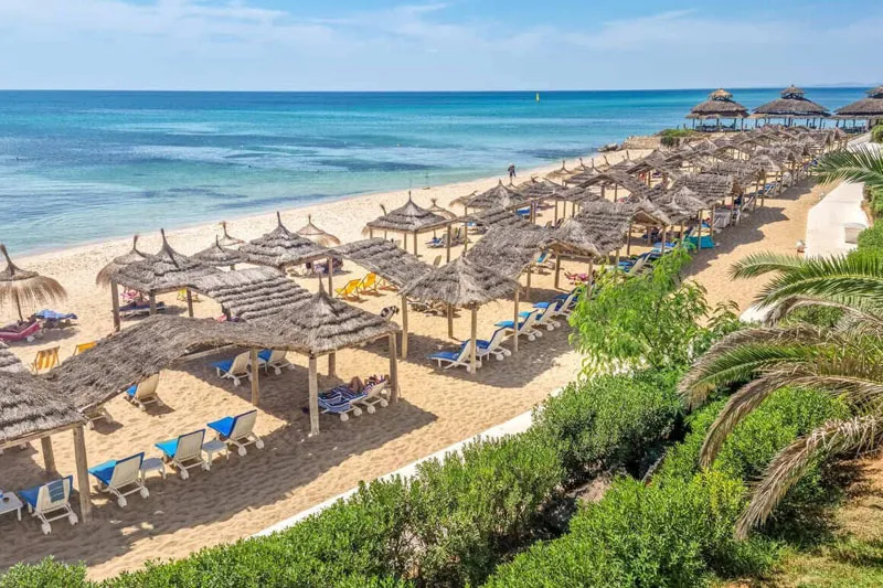 słoneczna plaża w kurorcie w Tunezji z turystami