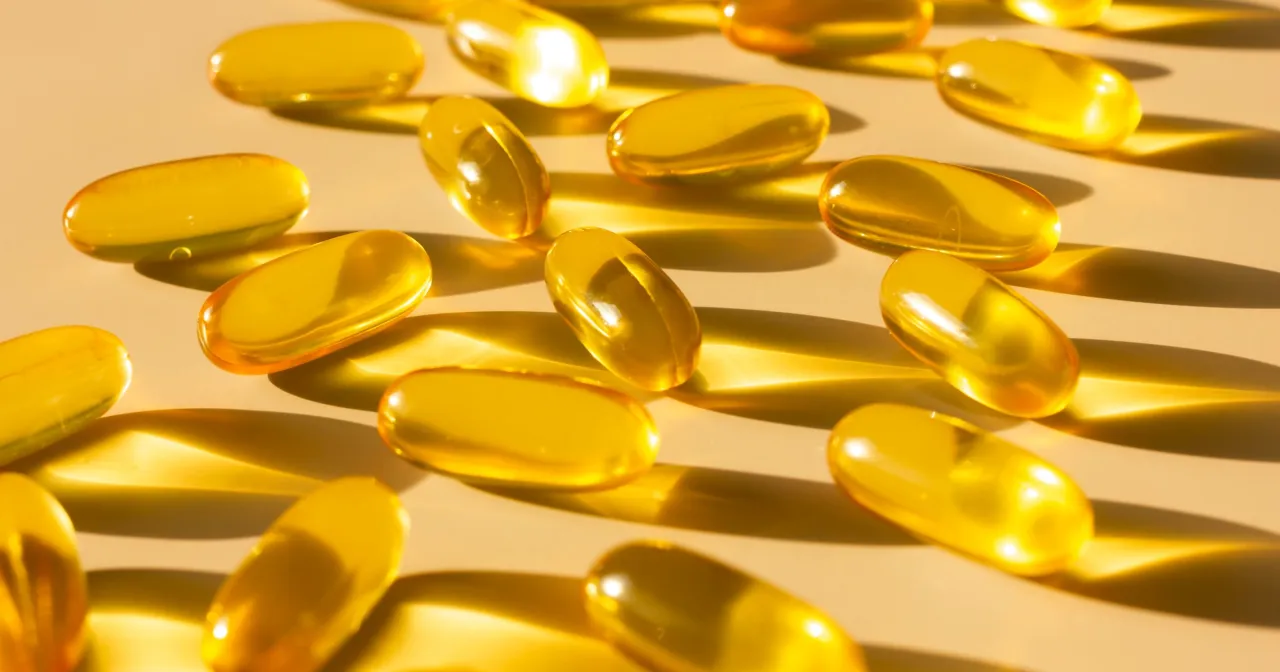 Żółte kapsułki, symbolizujące dietę wydłużającą telomery, rozrzucone na jasnym tle.