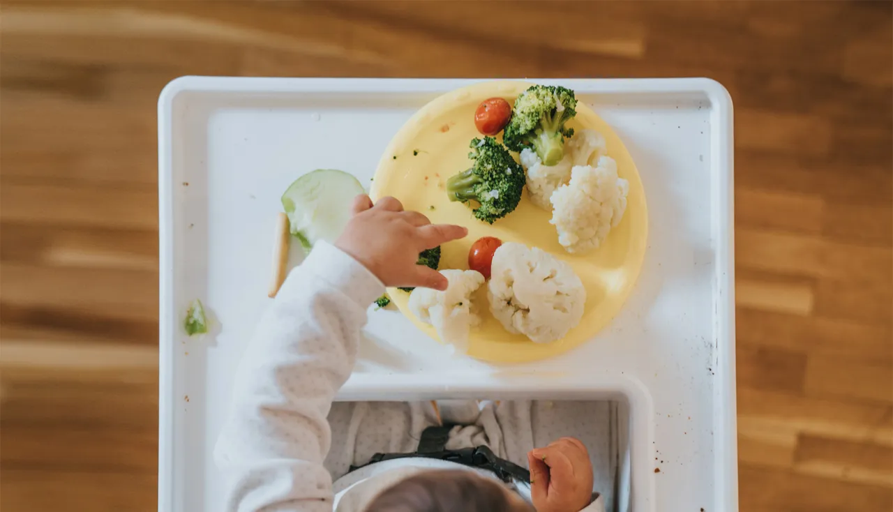 Dziecko wybiera warzywa z talerzyka, część posiłku z tygodniowy jadłospis dla rocznego dziecka.