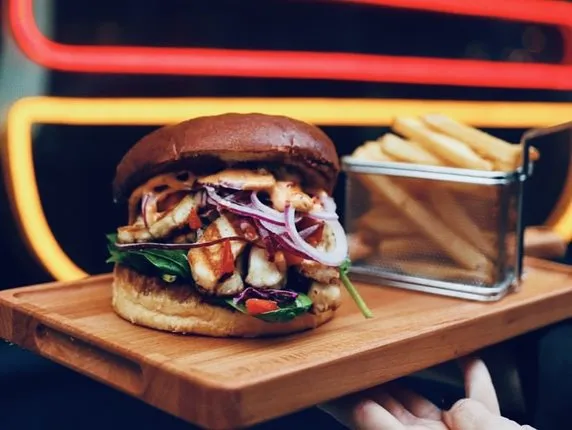 Burger przekrojony na p&oacute;ł na desce do serwowania