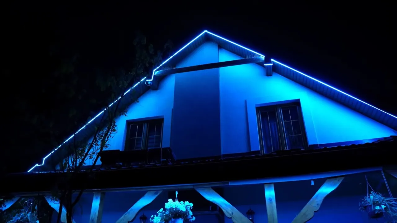 Niebieskie lampy w podbitce podkreślają architekturę domu nocą, tworząc magiczny nastrój.