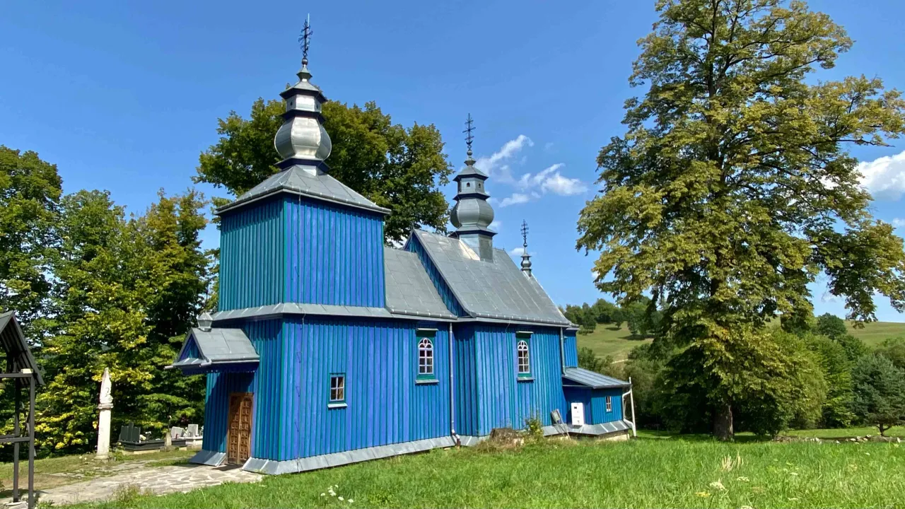 Drewniana, błękitna cerkiew na Podkarpaciu, otoczona zielenią. Idealne miejsce, by odkryć, co zwiedzić na Podkarpaciu.