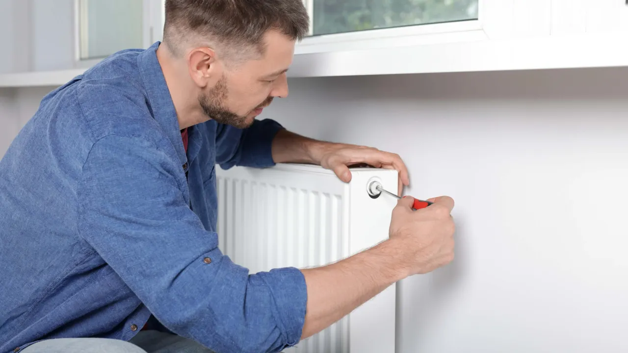 osoba mierząca temperaturę w mieszkaniu, odpowietrzanie kaloryfera