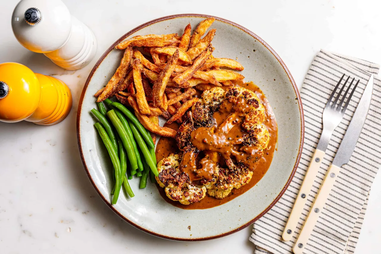 Blumenkohlsteaks mit Gew&uuml;rzen und Dressing auf einem Teller