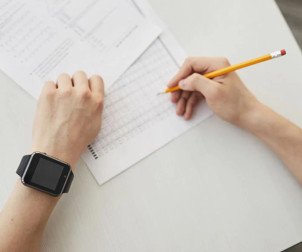 Uczeń piszący egzamin maturalny z angielskiego, zegar