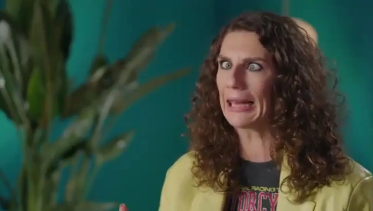 Wiola stand up! Zaskoczona kobieta z kręconymi włosami i wykrzywioną miną, ubrana w żółtą marynarkę.