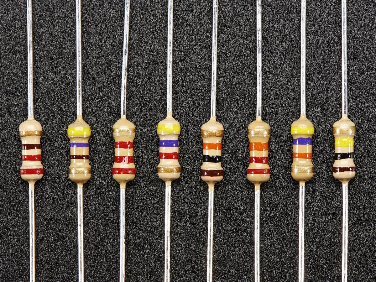 Rząd kolorowych pasków na obudowach symboli rezystorów, każdy z dwoma metalowymi wyprowadzeniami.