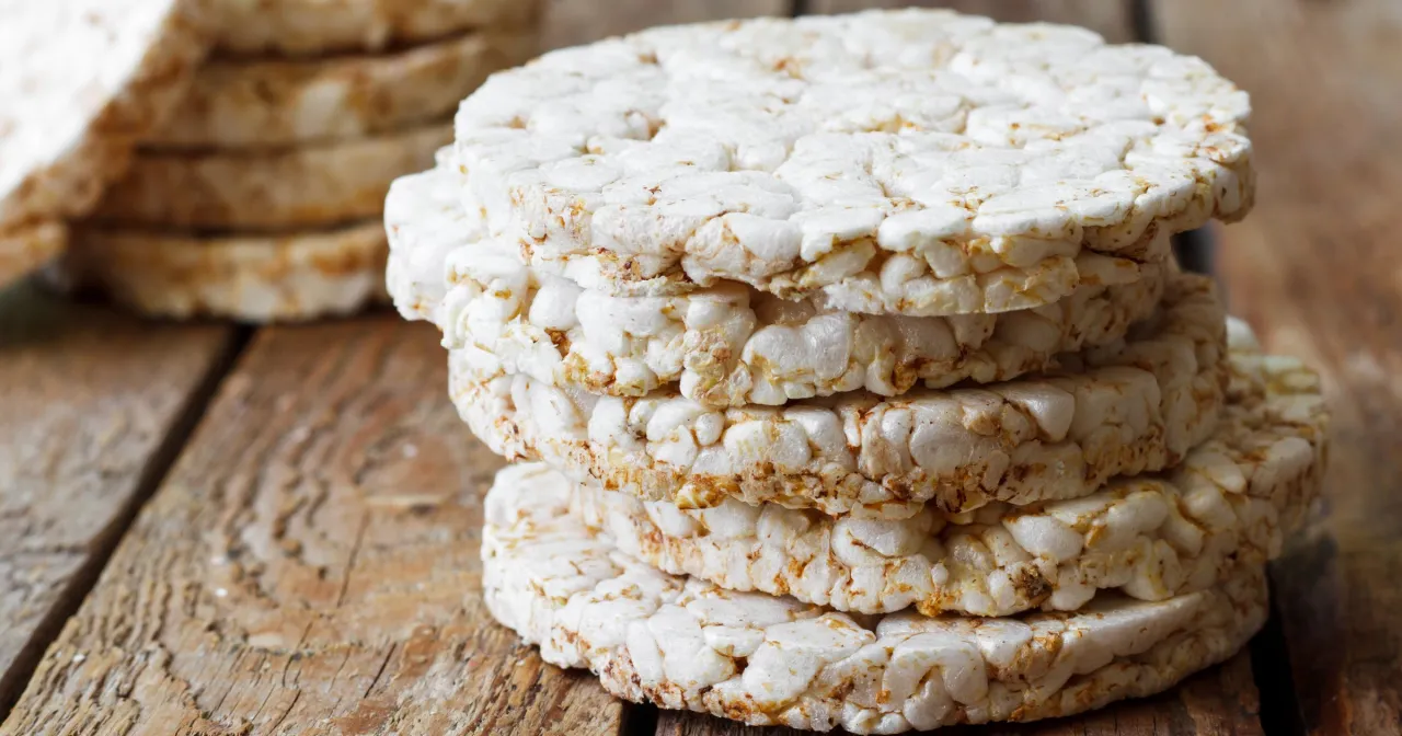 Stos wafli ryżowych na drewnianym stole. Czy wafle ryżowe są zdrowe? To lekkie i chrupiące przekąski, idealne na szybką przekąskę.