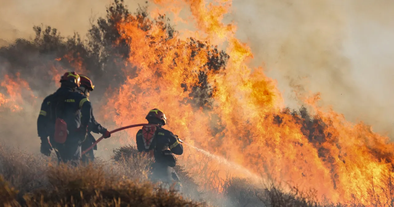 Strażacy walczą z pożarem. Jeden z nich trzyma wąż, drugi polewa płomienie wodą. Czy kreta czy jest bezpiecznie?