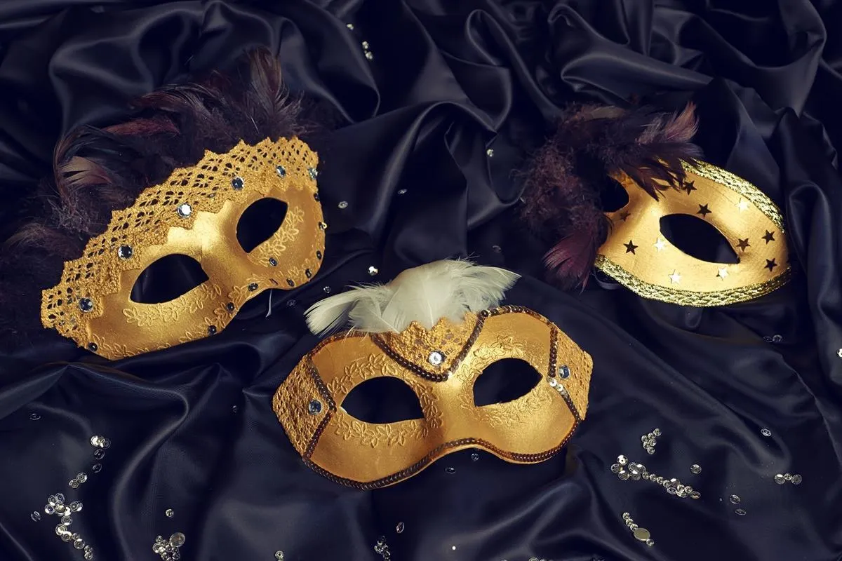 Złote maski karnawałowe z pi&oacute;rami i cekinami na czarnym jedwabiu. Inspiracja, jak zrobić maskę karnawałową.