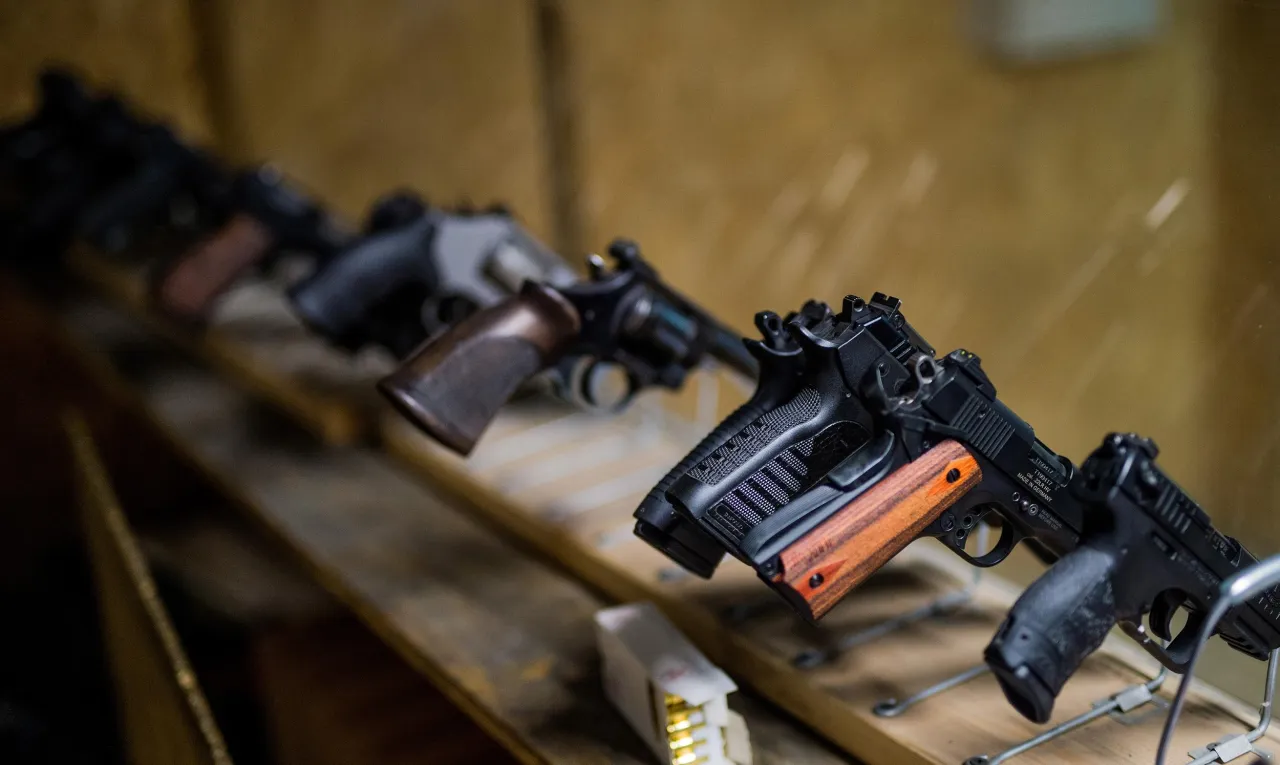 Rzędy broni krótkiej, w tym rewolwerów i pistoletów, na drewnianej półce. Czy myśliwy może mieć broń krótką? Tak, w zależności od przepisów.