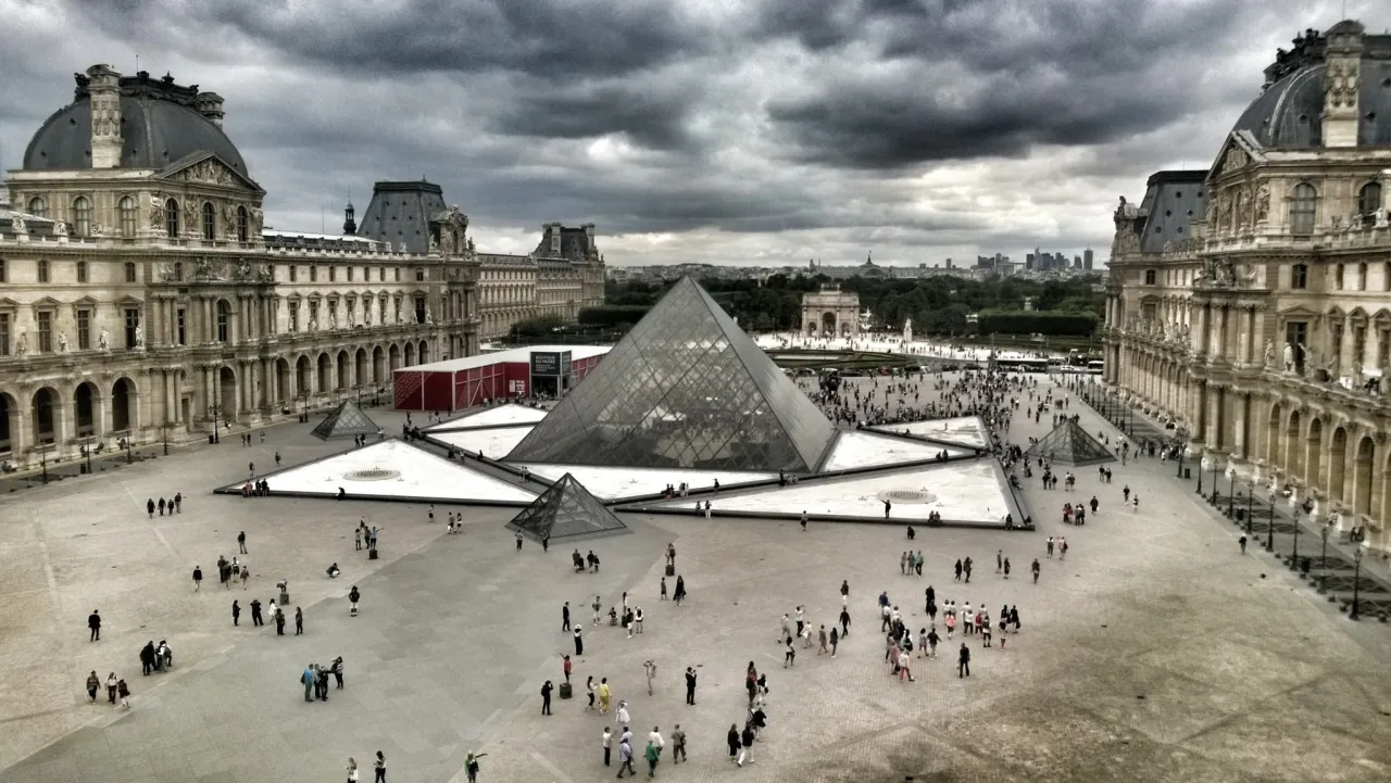 Tłum ludzi zwiedza Luwr, podziwiając piramidę i architekturę. Ile czasu zwiedza się Luwr? Tyle, ile potrzeba, by poczuć magię tego miejsca.