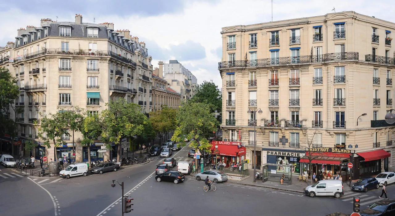 Tętniąca życiem ulica w Paryżu, z kawiarniami i sklepami. Czy 15 dzielnica Paryża jest bezpieczna? Wygląda na to, że tak, ludzie spacerują i jeżdżą na rowerach.